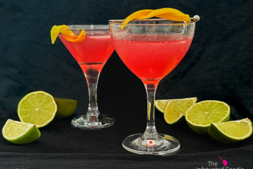 Picture of two cosmpolitan cocktails with lime wedges on a black background with